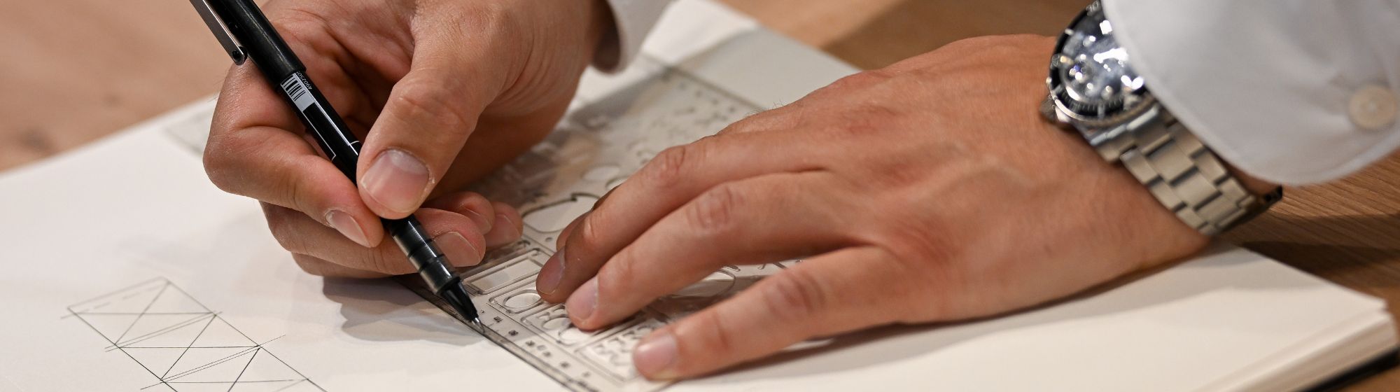 Architecte dessinant un plan technique avec règle et crayon lors d’un atelier maison à Home & Co Paris