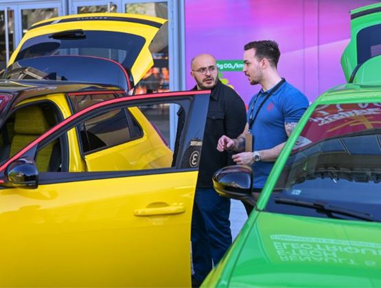 Visiteur échangeant avec un exposant devant une voiture électrique colorée sur Auto Mobil Paris