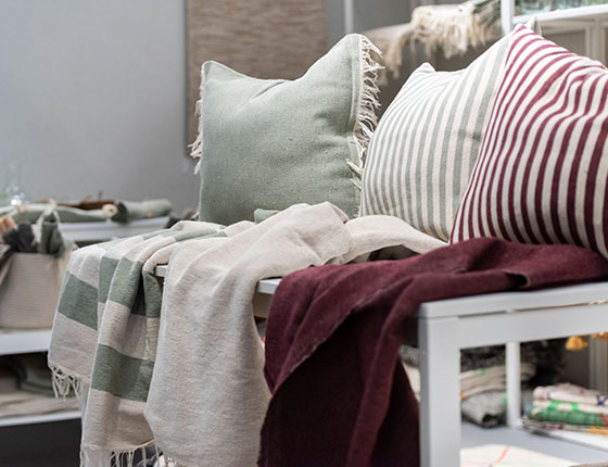 coussins et légères couvertures vert et bordeau sur un banc